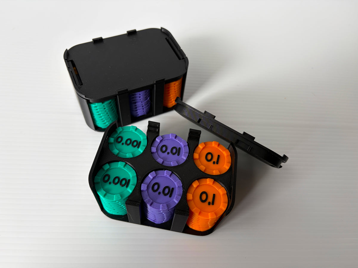 Boitier noir ouvert contenant des piles de jetons turquoise (0,001), violets (0,01) et orange (0,1), avec un boitier fermé derrière